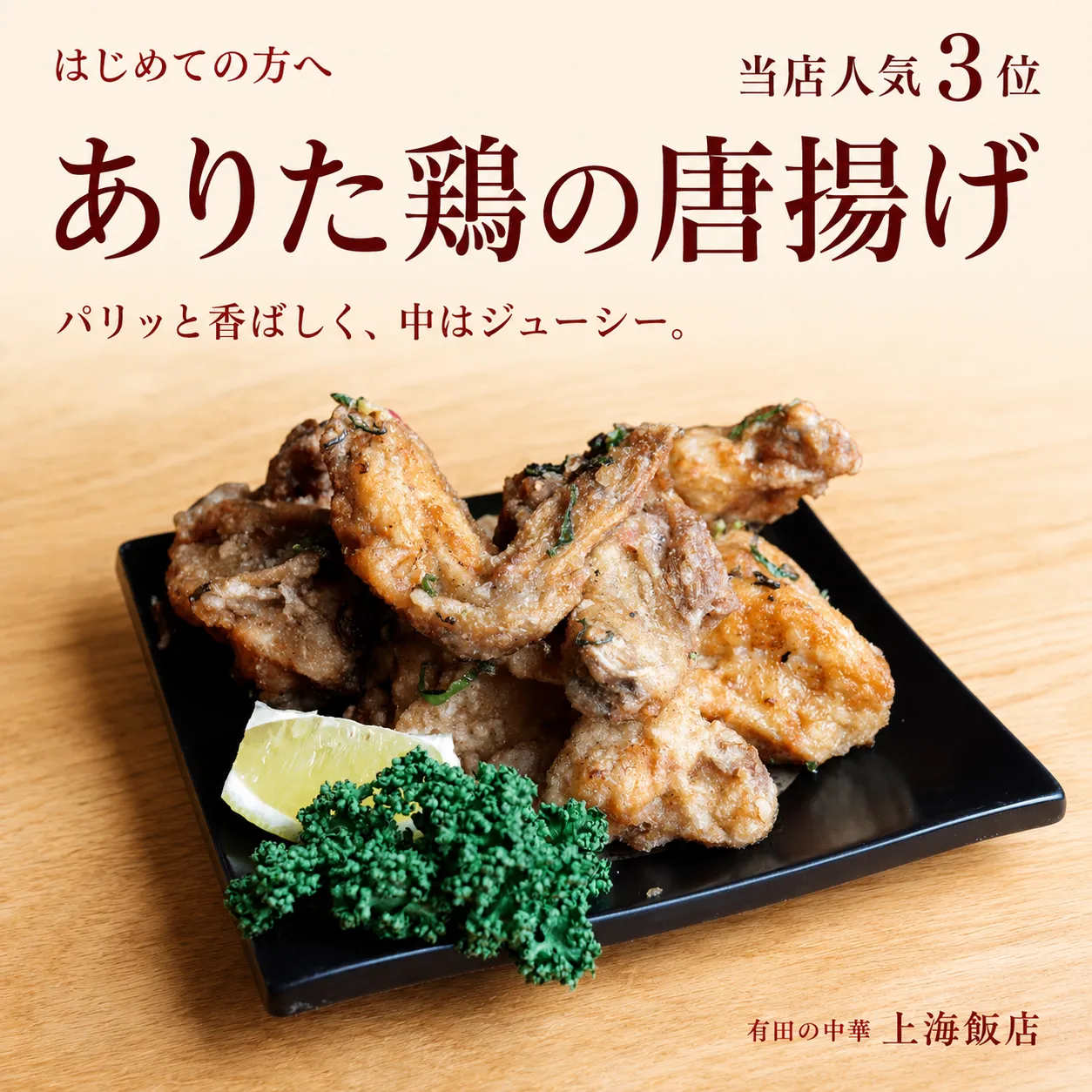 上海飯店の人気3位、ありた鶏の唐揚げ。黒い角皿に香ばしく揚げた鶏肉とレモンを盛り付けた一皿