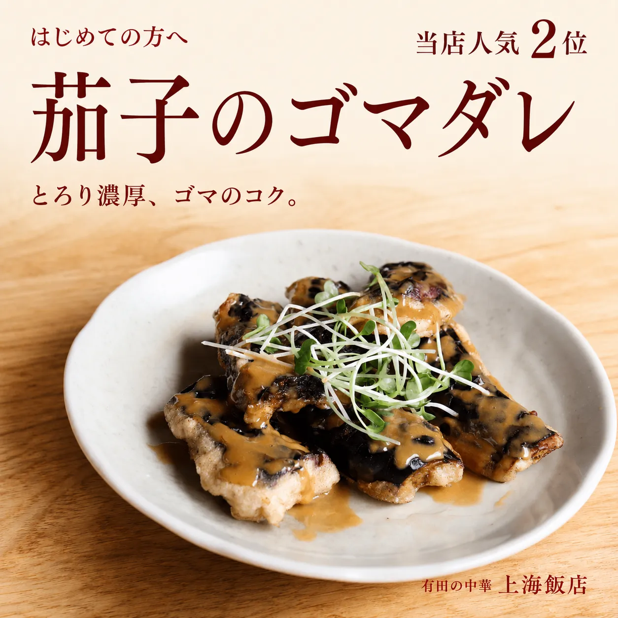 上海飯店の人気2位、茄子のゴマダレ。白い丸皿の茄子に濃厚なゴマダレをかけ、カイワレを添えた一皿