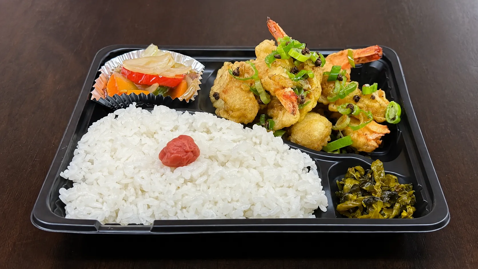 上海飯店の海老イカ天弁当。海老とイカの天ぷら、ご飯、野菜の餡かけを詰めてテーブルに置いた様子